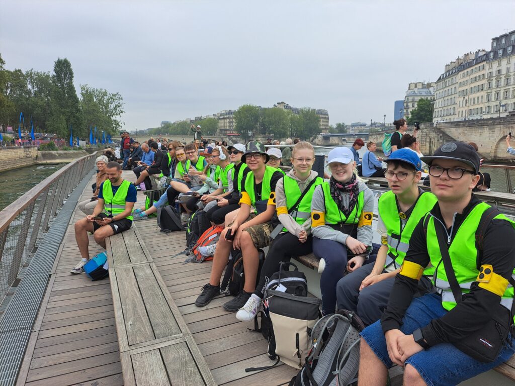 Gruppenfoto der Reisegruppe auf dem Oberdeck eines Seine-Rundfahrtsschiffes.