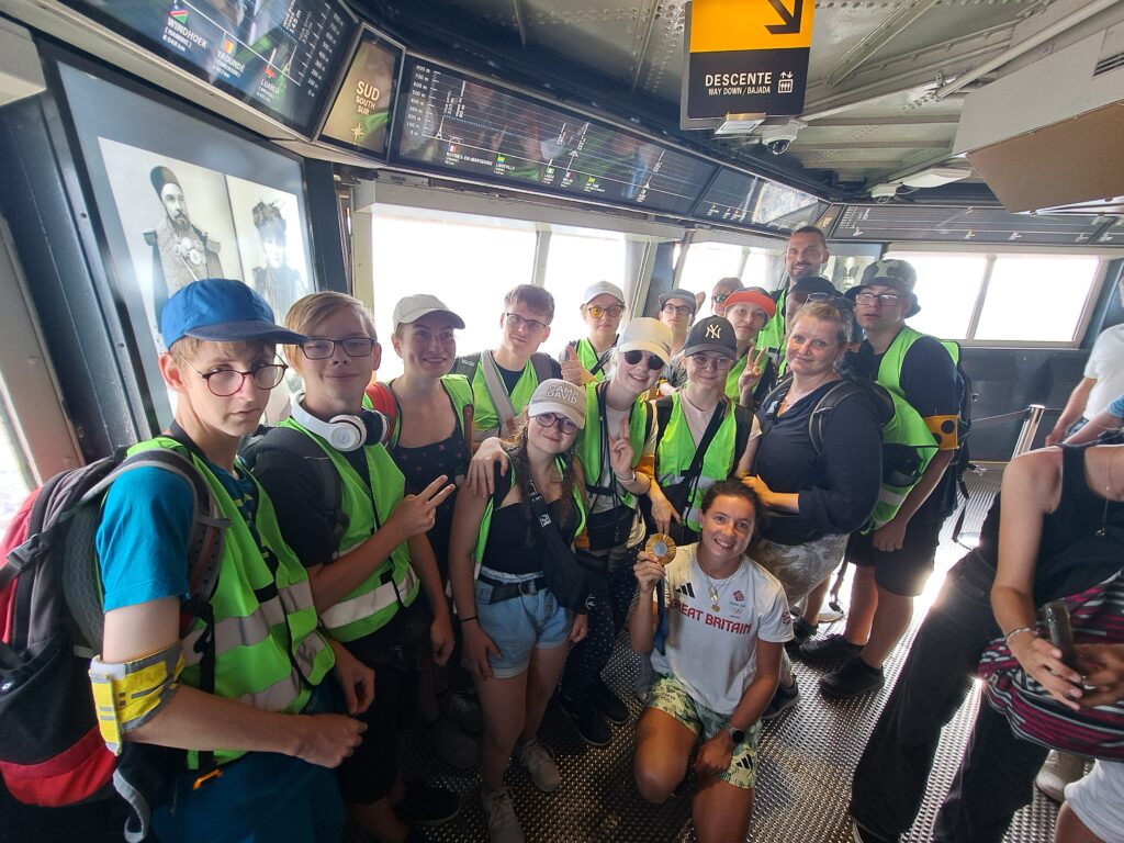 Gruppenfoto im Inneren der Spitze des Eiffelturms. Zu sehen ist die Reisegruppe und eine Medaillengewinnerin, die ihre Medaille in der Hand hält.