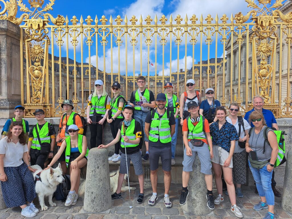 Gruppenfoto vor den goldenen Toren des Schlosses Versailles.