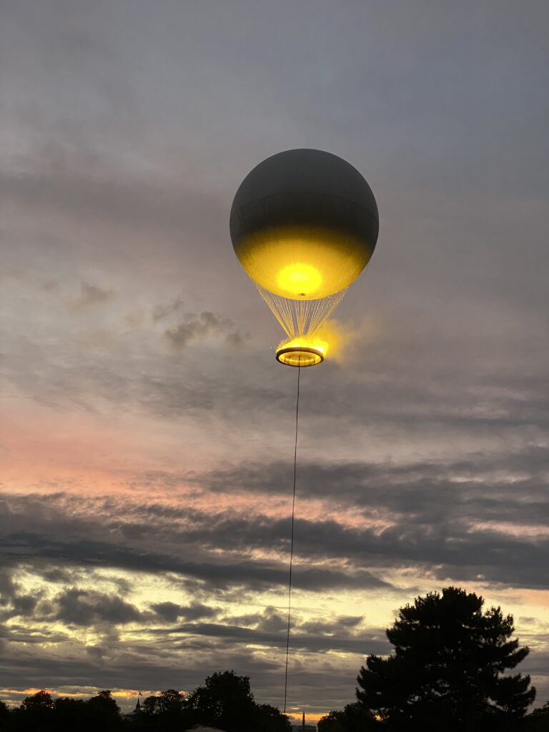 Der Heißluftballon als Symbol des olympischen Feuers hängt am Pariser Himmel, es dämmert bereits ein wenig